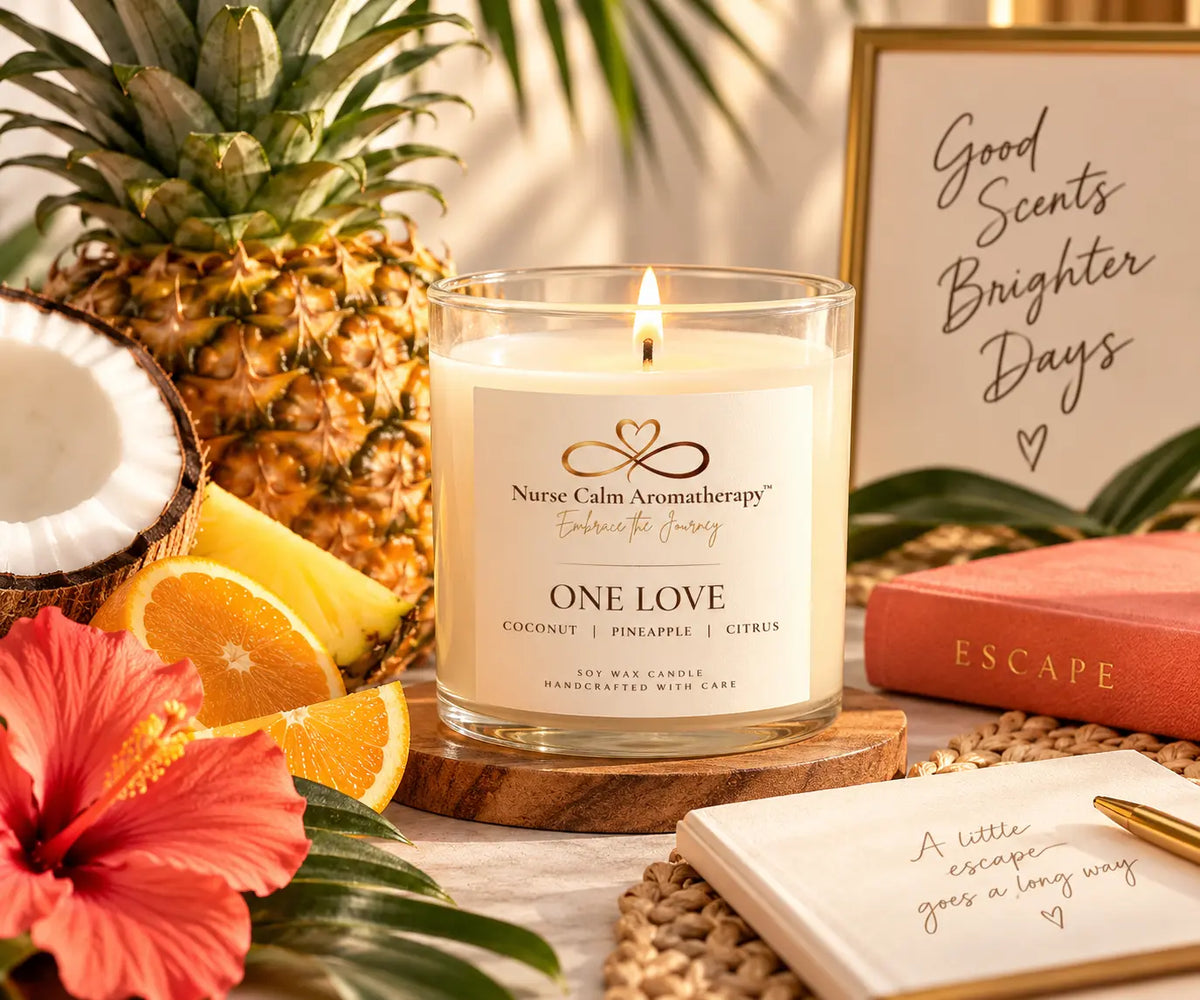 Lit Nurse Calm Aromatherapy™ One Love soy candle styled with pineapple, coconut, citrus slices, hibiscus, and warm tropical décor, creating a bright, relaxing escape-inspired scene.