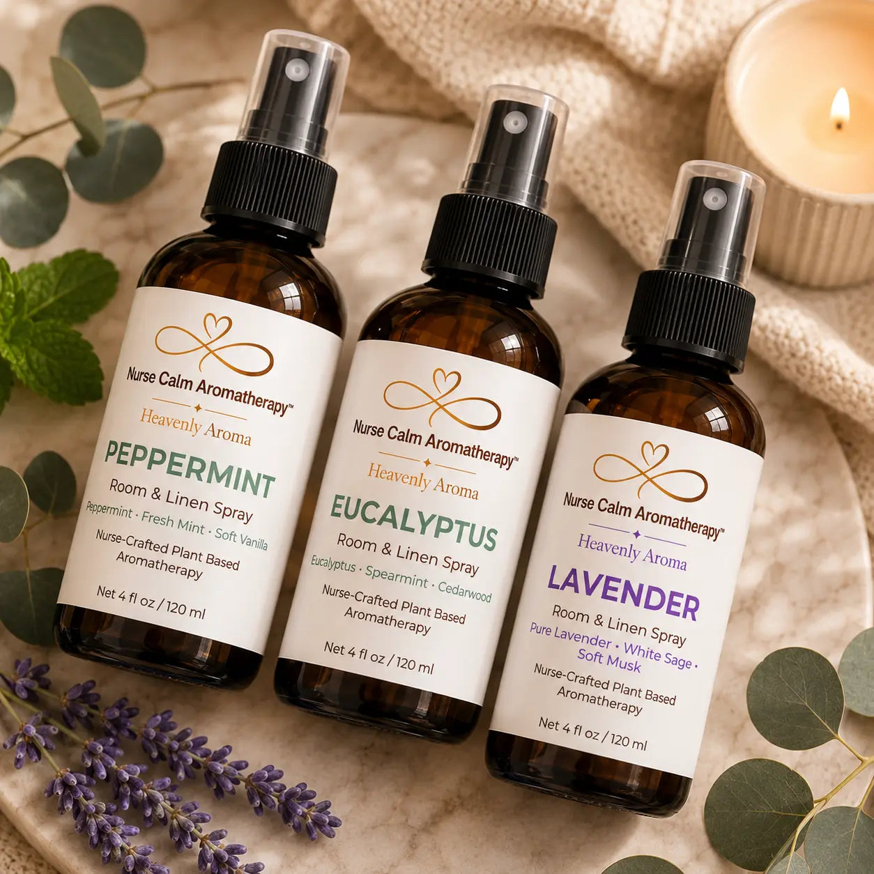 Close-up of the Essentials Bundle featuring Peppermint, Eucalyptus, and Lavender Room & Linen Sprays arranged on a marble tray with eucalyptus, mint, lavender, and candle décor.