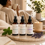 Woman enjoying a peaceful self-care moment with the Essentials Bundle of Peppermint, Eucalyptus, and Lavender Room & Linen Sprays in a warm, relaxing home environment.