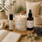 Nurture Calm Aromatherapy products including a candle, rollerball, and spray bottle on a wooden tray with flowers and a book.