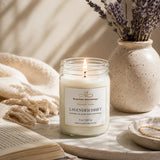 Candle in a glass jar labeled 'Nurse Calm Aromatherapy' with lavender in a vase on a neutral background